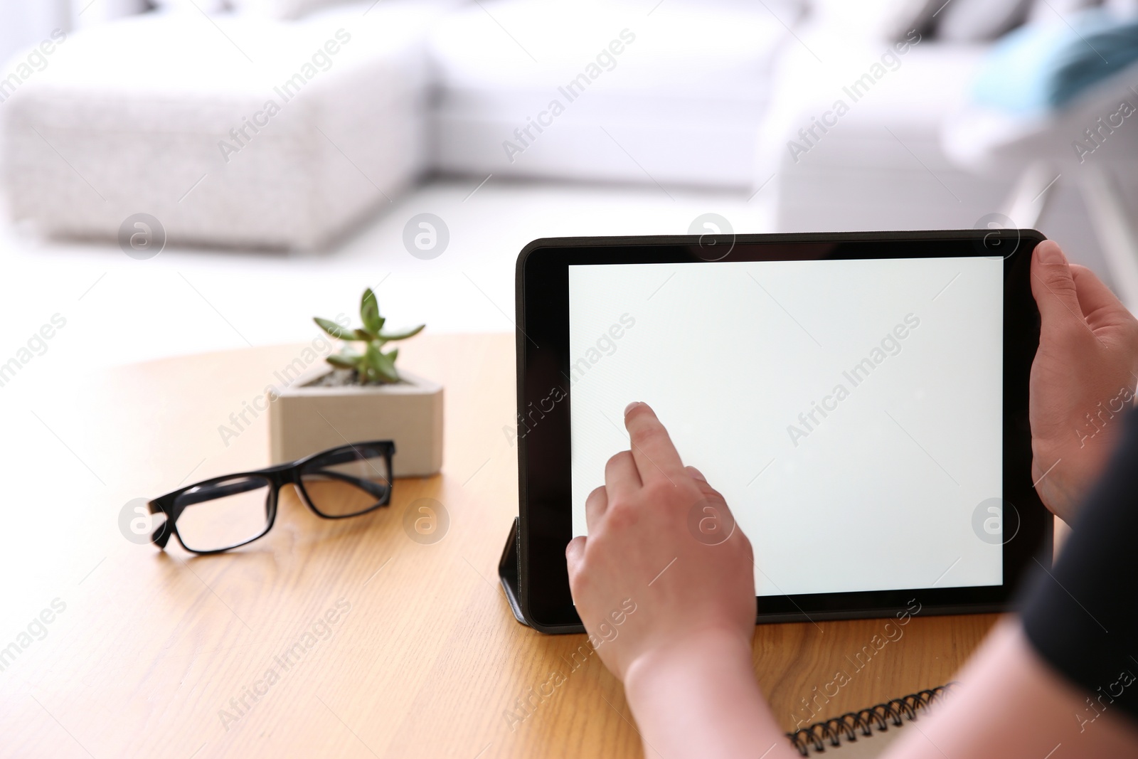 Photo of Woman working with modern tablet at wooden table, closeup. Space for design