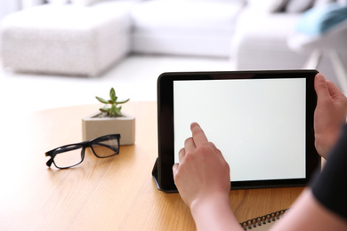 Woman working with modern tablet at wooden table, closeup. Space for design