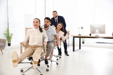 Photo of Office employees riding chairs at workplace. Space for text
