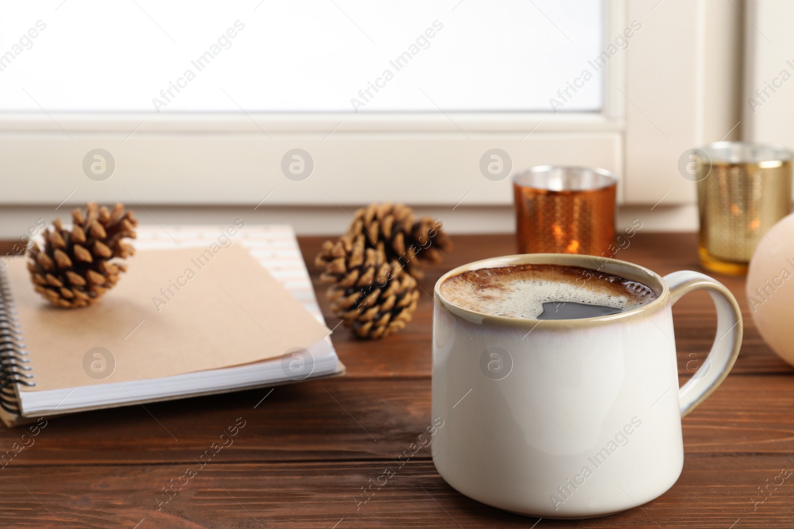 Photo of Composition with cup of hot coffee and notebooks on windowsill. Winter drink