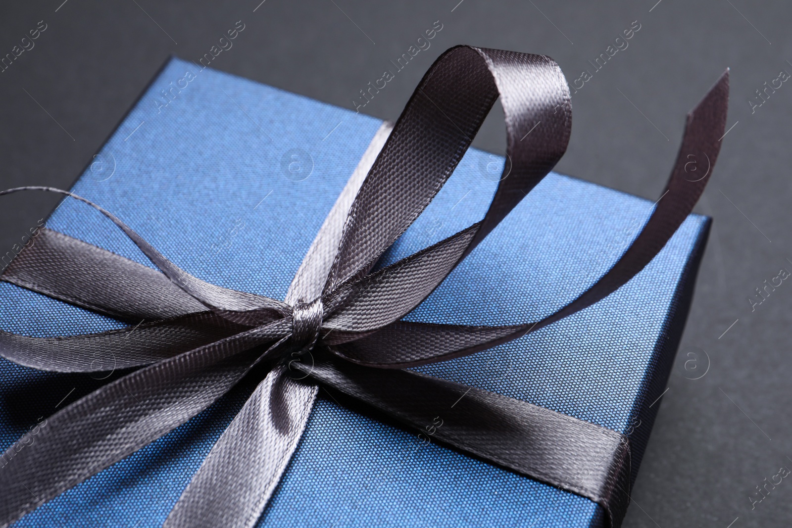 Photo of Blue gift box on black background, closeup