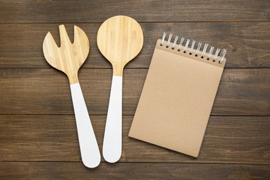 Photo of Blank recipe book and kitchen utensils on wooden table, flat lay. Space for text