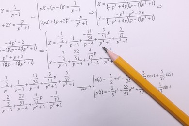 Sheet of paper with mathematical formulas and pencil, top view