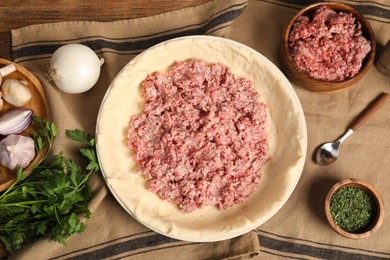 Photo of Flat lay composition with raw dough and ingredients on wooden table. Baking meat pie
