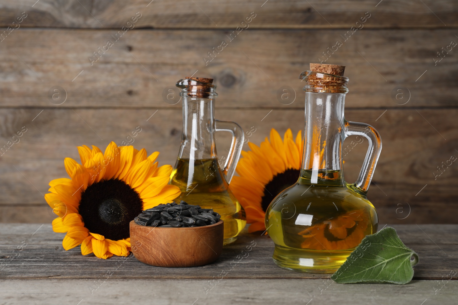 Photo of Sunflower cooking oil, seeds and yellow flowers on wooden table