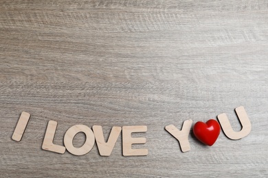 Photo of Phrase I Love You made of decorative heart and letters on wooden background, flat lay. Space for text