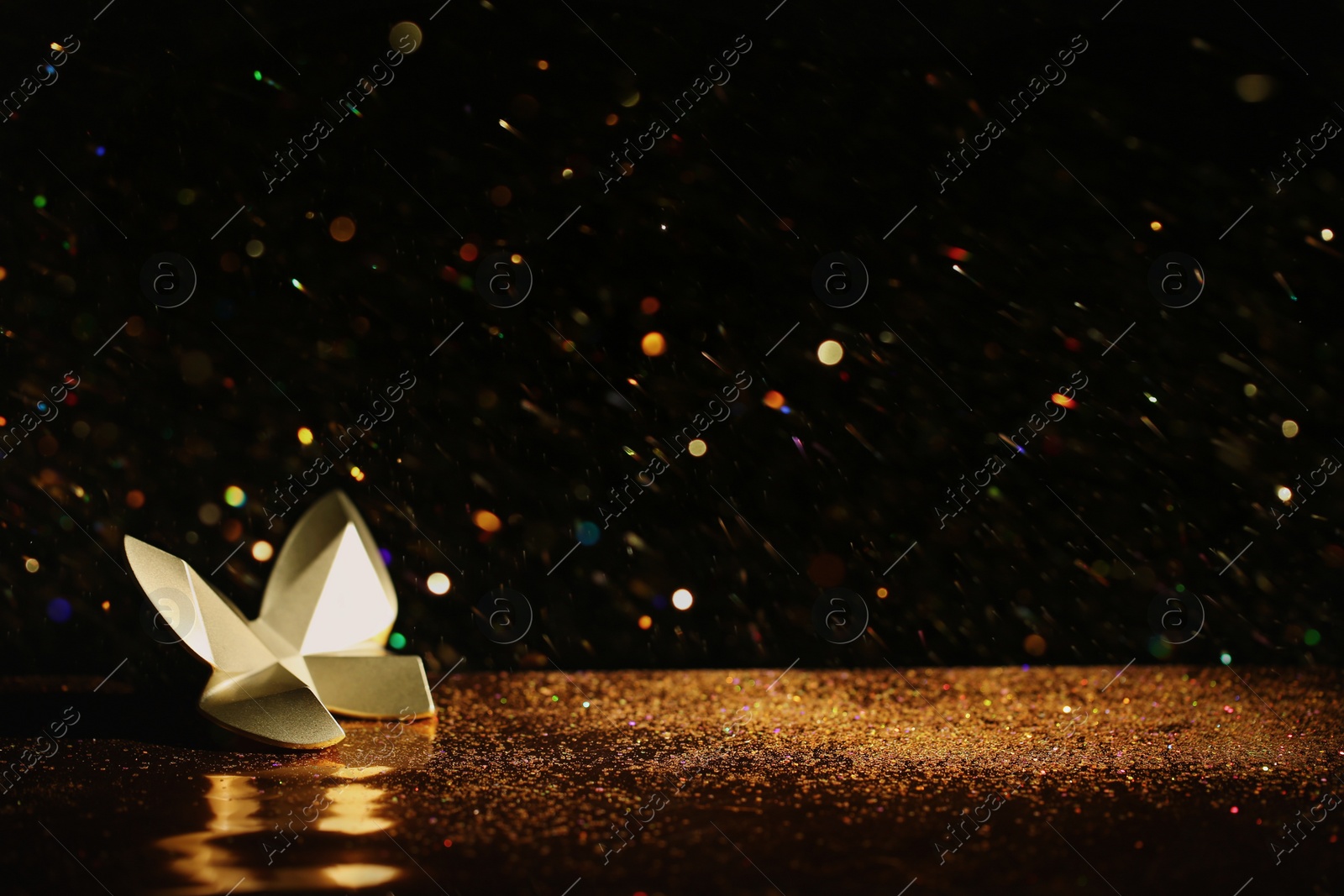 Photo of Golden glitter and decorative butterfly against black background. Space for text
