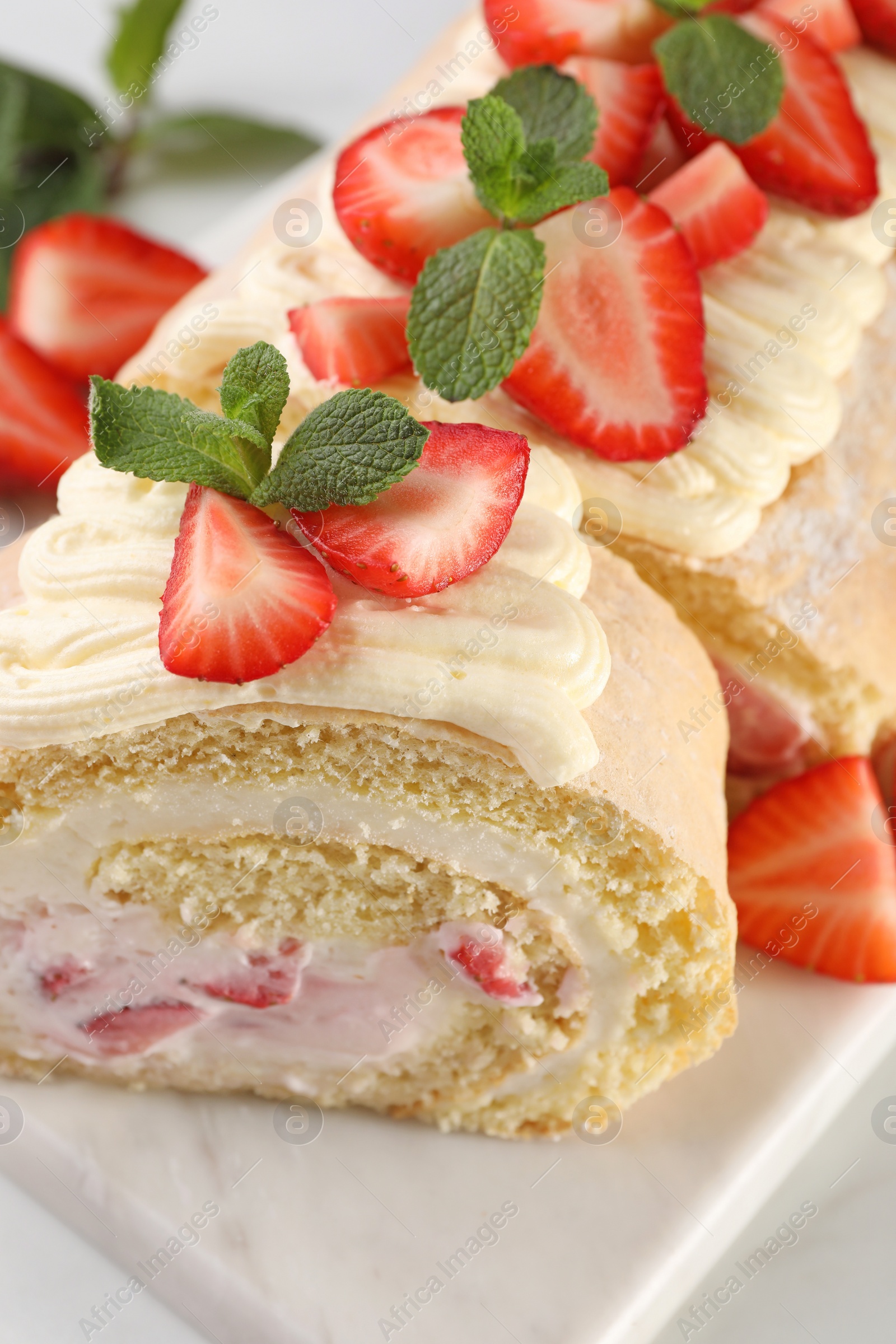 Photo of Delicious cake roll with strawberries and cream on white table, closeup