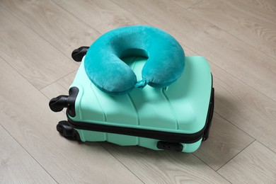 Photo of Turquoise travel pillow and suitcase on floor