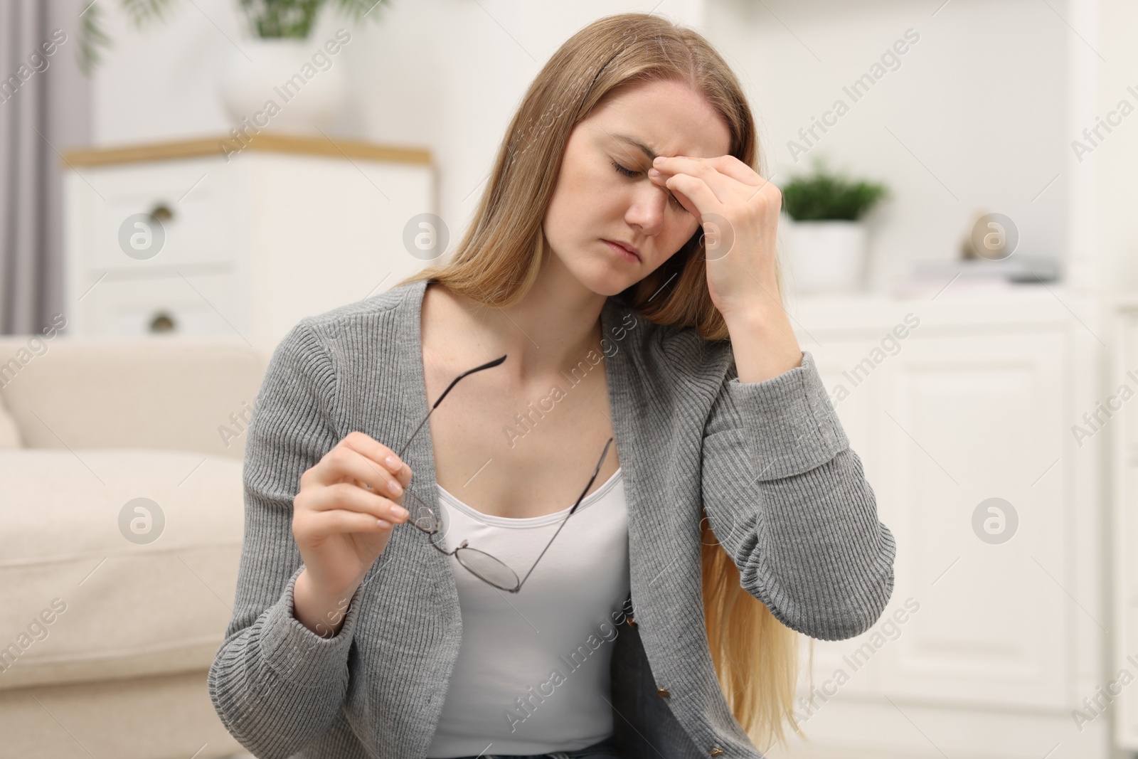 Photo of Overwhelmed young woman with glasses suffering from headache at home