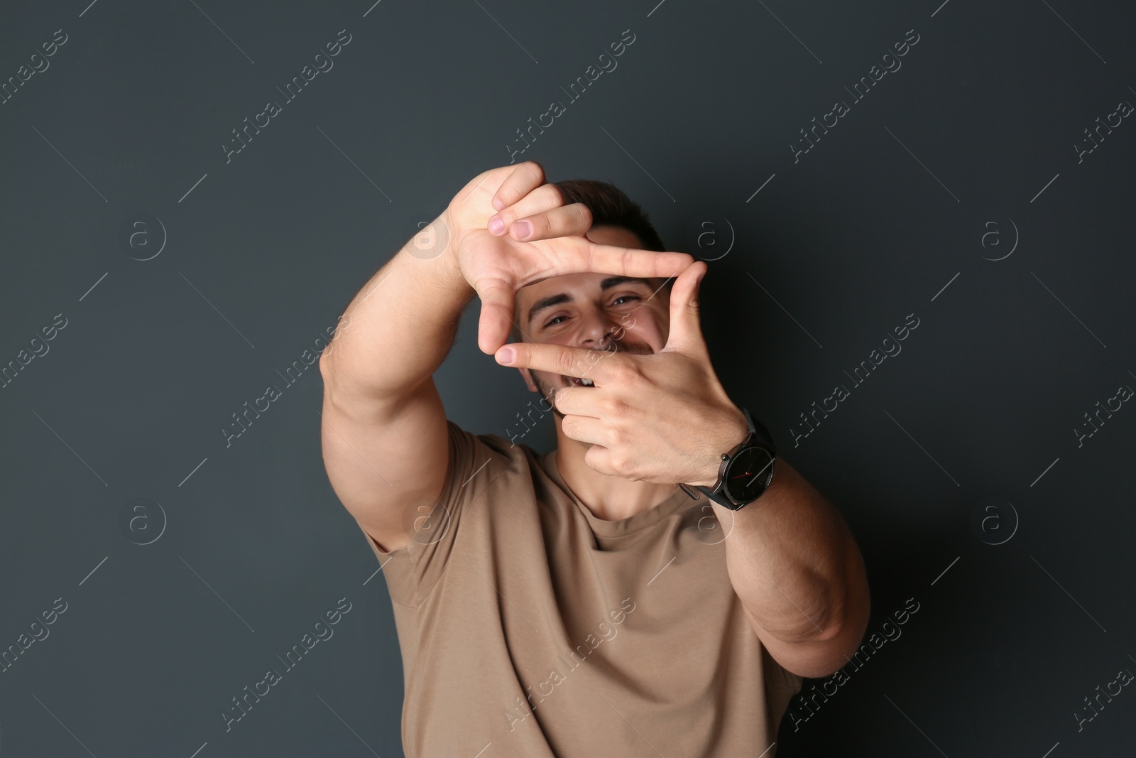 Photo of Portrait of happy man making frame with hands on dark background