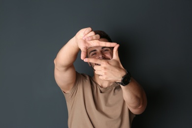 Photo of Portrait of happy man making frame with hands on dark background