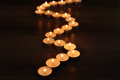 Burning candles on wooden table in darkness