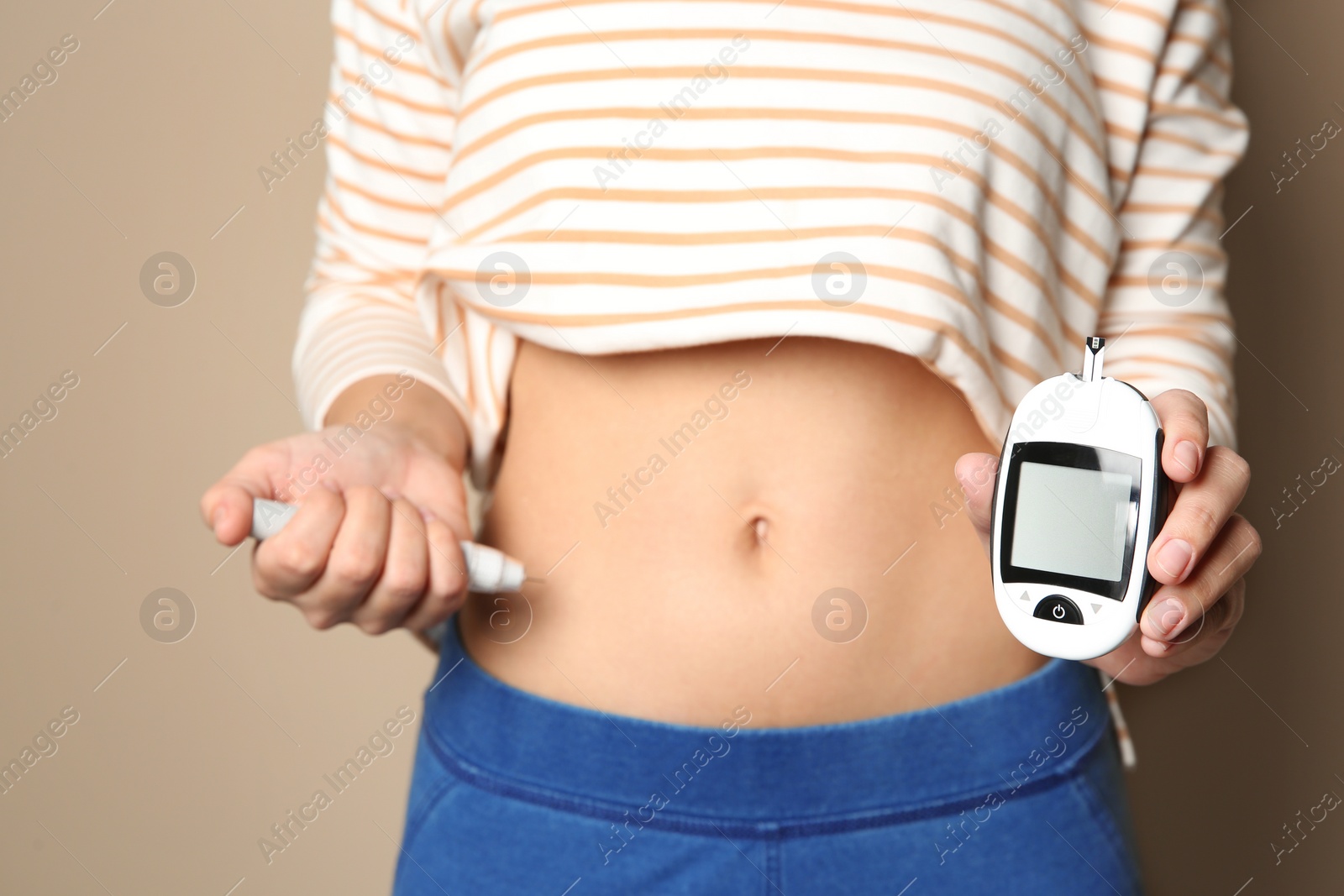 Photo of Woman with insulin syringe and glucometer on color background, closeup. Diabetes disease
