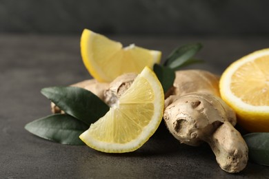 Photo of Fresh lemon and ginger on grey table, closeup