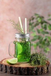 Mason jar of homemade refreshing tarragon drink with lemon slices and sprigs on wooden stump