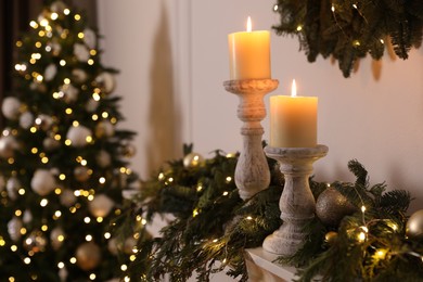 Burning candles and Christmas decor on mantel shelf indoors