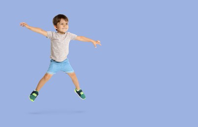 Image of Happy boy jumping on light blue background, space for text