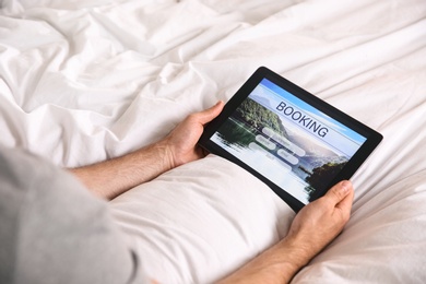 Photo of Man booking tickets online in bed, closeup. Travel agency concept
