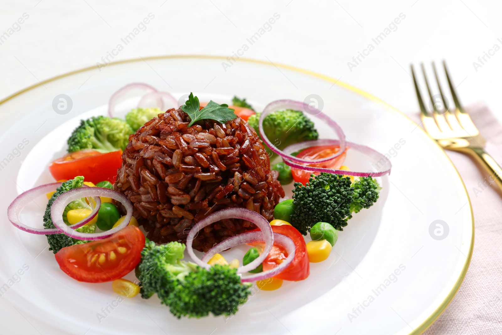 Photo of Plate of boiled brown rice with vegetables served on table, closeup