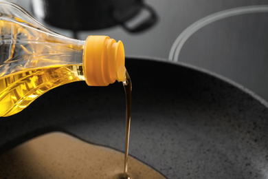 Pouring cooking oil from bottle into frying pan, closeup