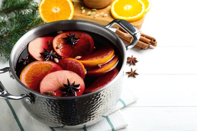 Photo of Delicious mulled wine and ingredients on white wooden table