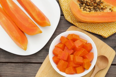 Photo of Tasty cut papaya fruits on wooden table, flat lay