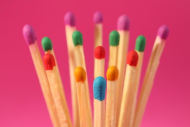 Photo of Matches with colorful heads on pink background, closeup