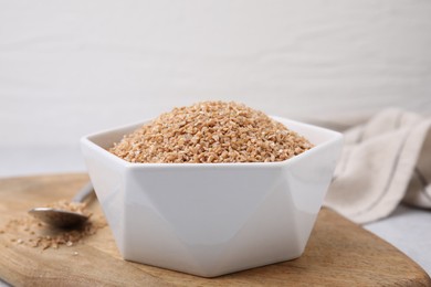 Photo of Dry wheat groats in bowl on light table, closeup