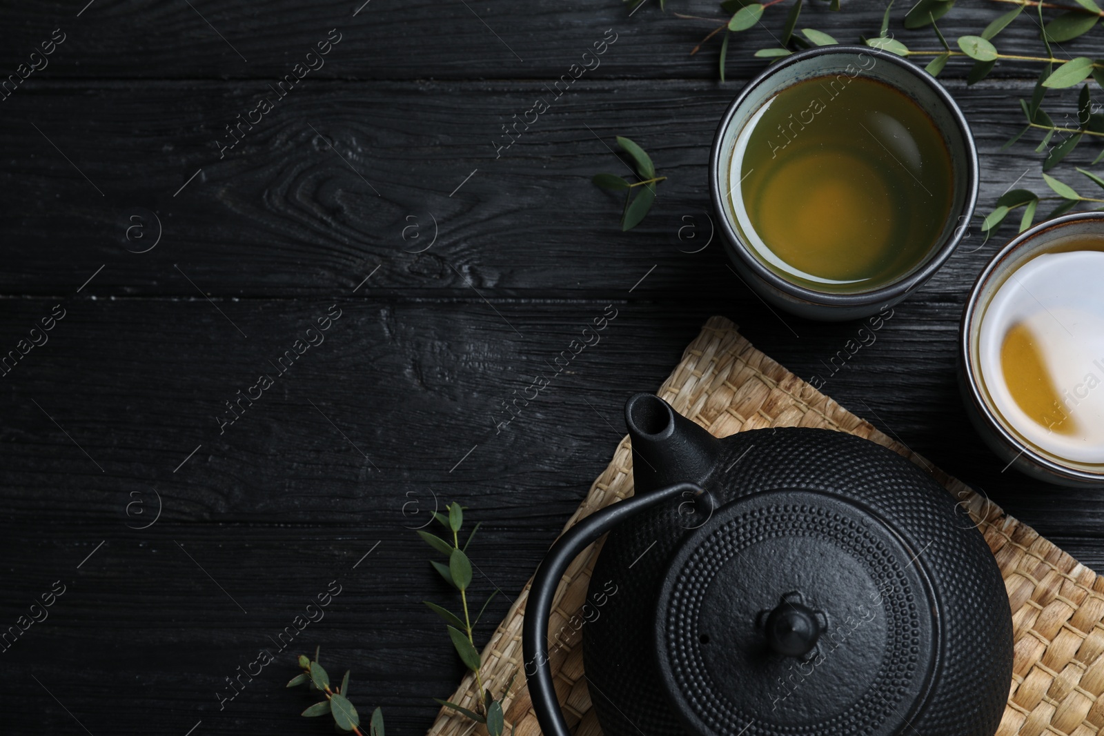 Photo of Aromatic eucalyptus tea on black wooden table, flat lay. Space for text