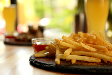 Photo of Delicious hot french fries with red sauce served on table, closeup