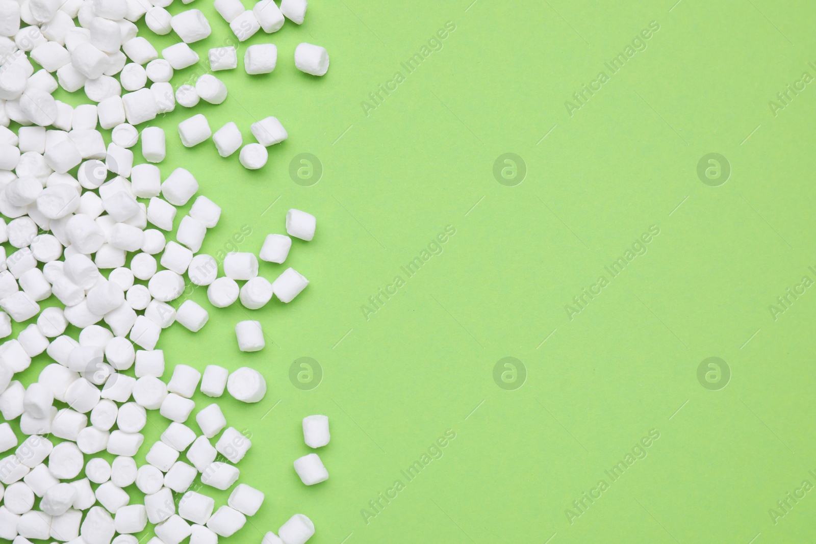 Photo of Delicious sweet marshmallows on light green background, flat lay. Space for text