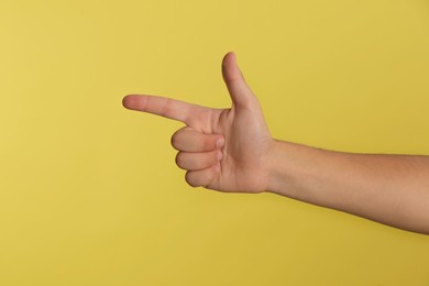 Photo of Teenage boy pointing at something on yellow background, closeup