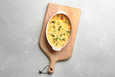 Photo of Tasty broccoli casserole on grey marble table, top view