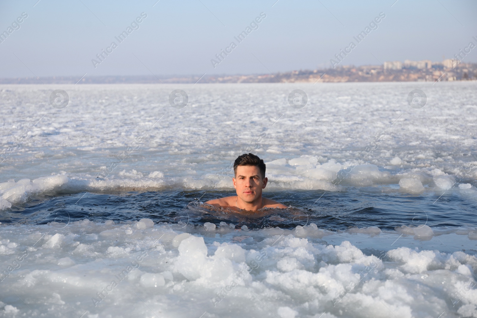 Photo of Man immersing in icy water on winter day. Baptism ritual