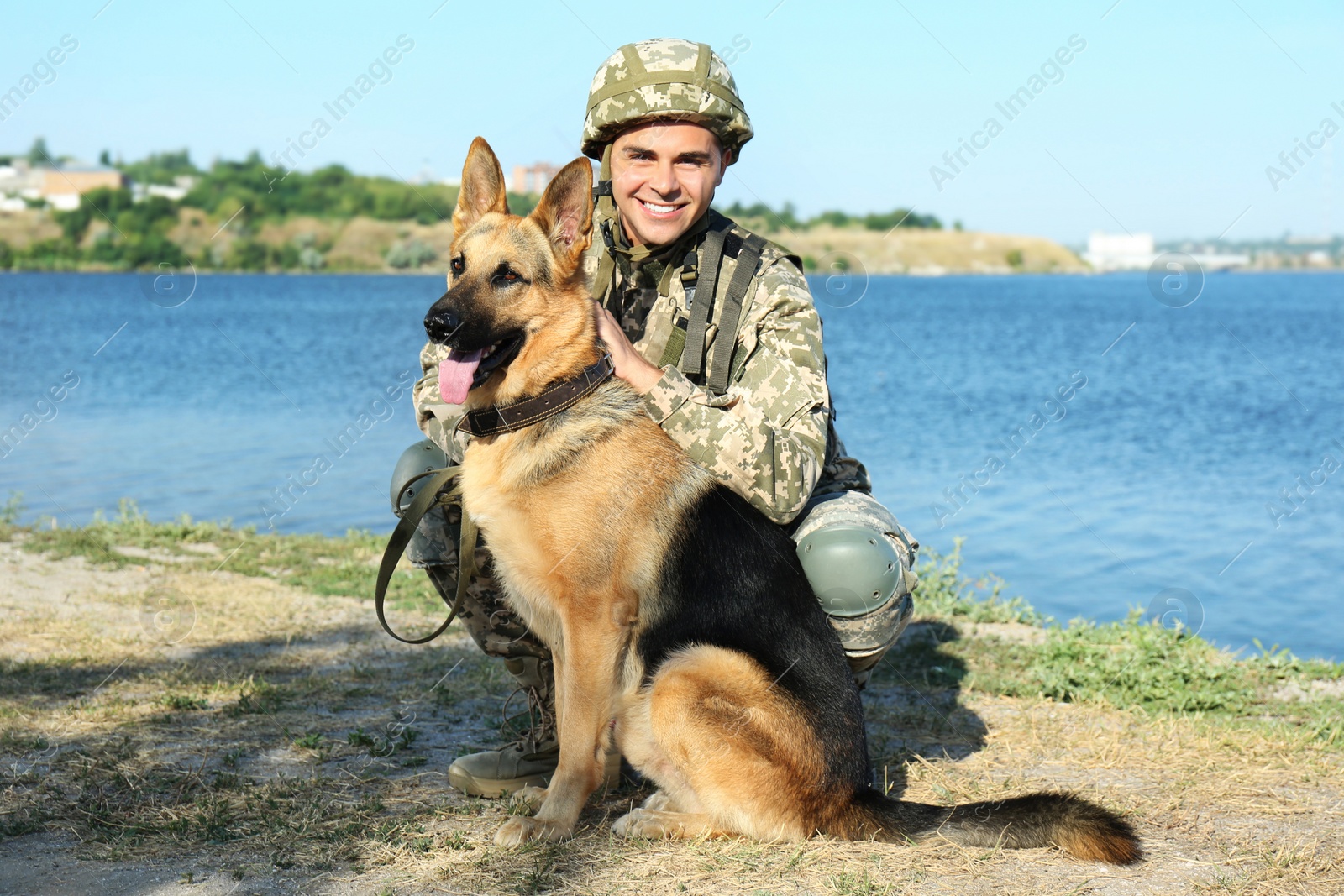 Photo of Man in military uniform with German shepherd dog near river