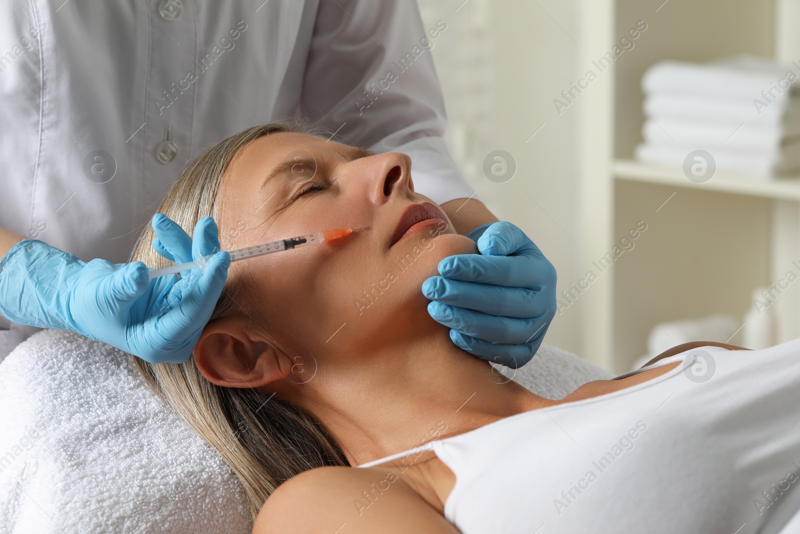 Photo of Doctor giving facial injection to senior woman in clinic. Cosmetic surgery