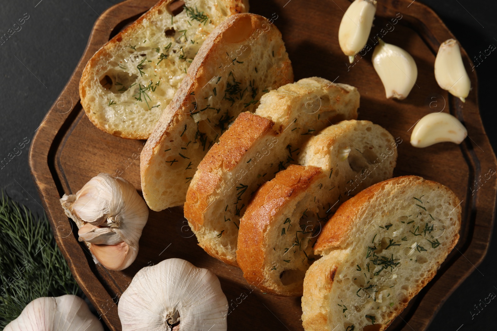 Photo of Tasty baguette with garlic and dill on grey table, top view