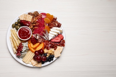 Photo of Plate of different appetizers with sauce on white wooden table, top view. Space for text