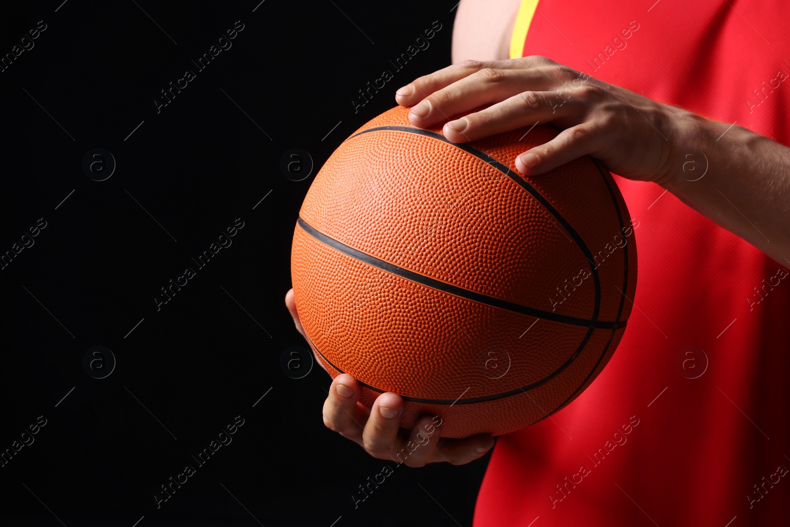 Photo of Athletic man with basketball ball on black background, closeup. Space for text