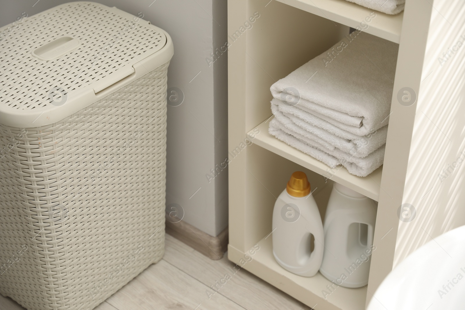 Photo of Shelving unit with stacked clean towels and detergents in bathroom