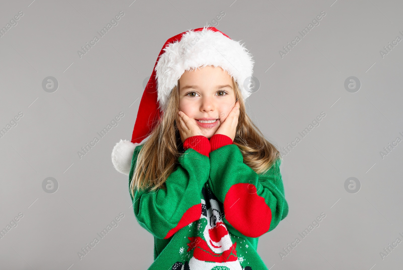 Photo of Cute child in Santa hat on grey background. Christmas celebration