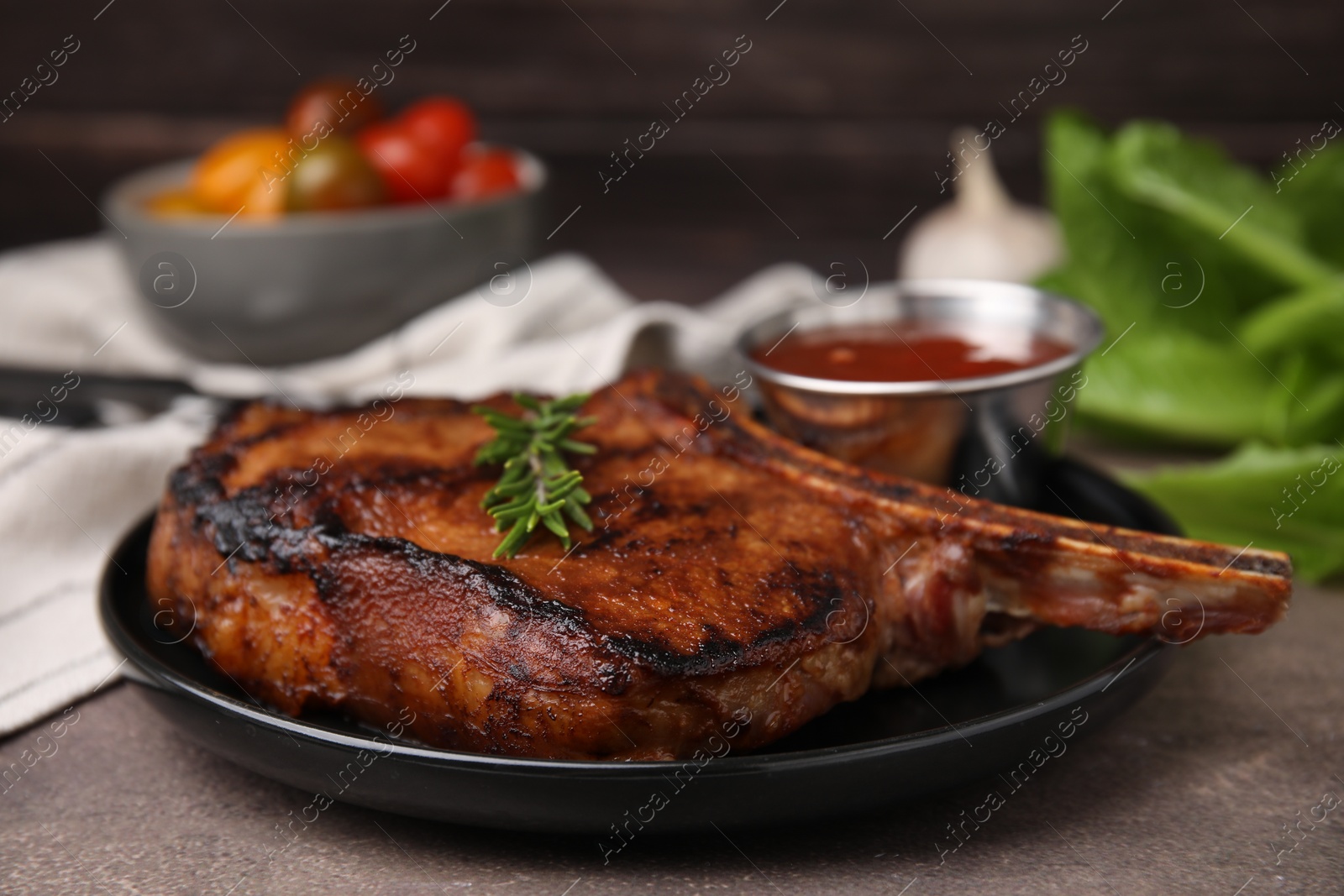 Photo of Tasty grilled meat, rosemary and marinade on brown textured table, closeup