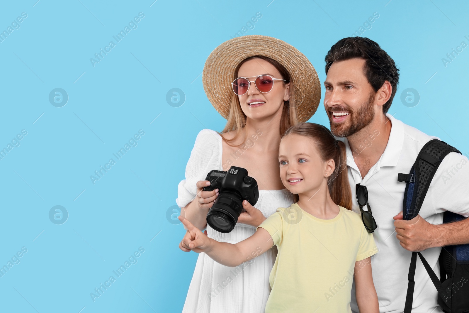 Photo of Happy family with camera on light blue background, space for text