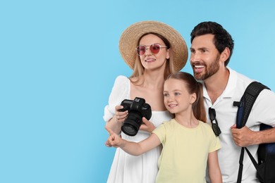 Photo of Happy family with camera on light blue background, space for text