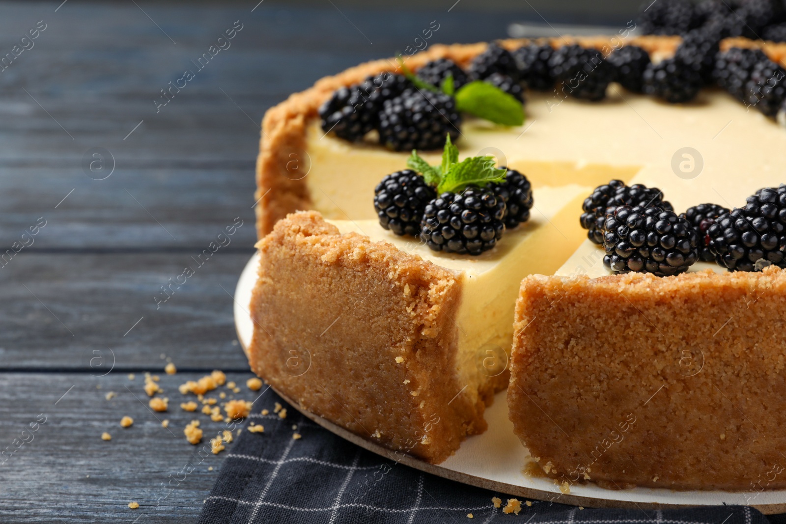 Photo of Sliced delicious cheesecake with blackberries on wooden table, closeup