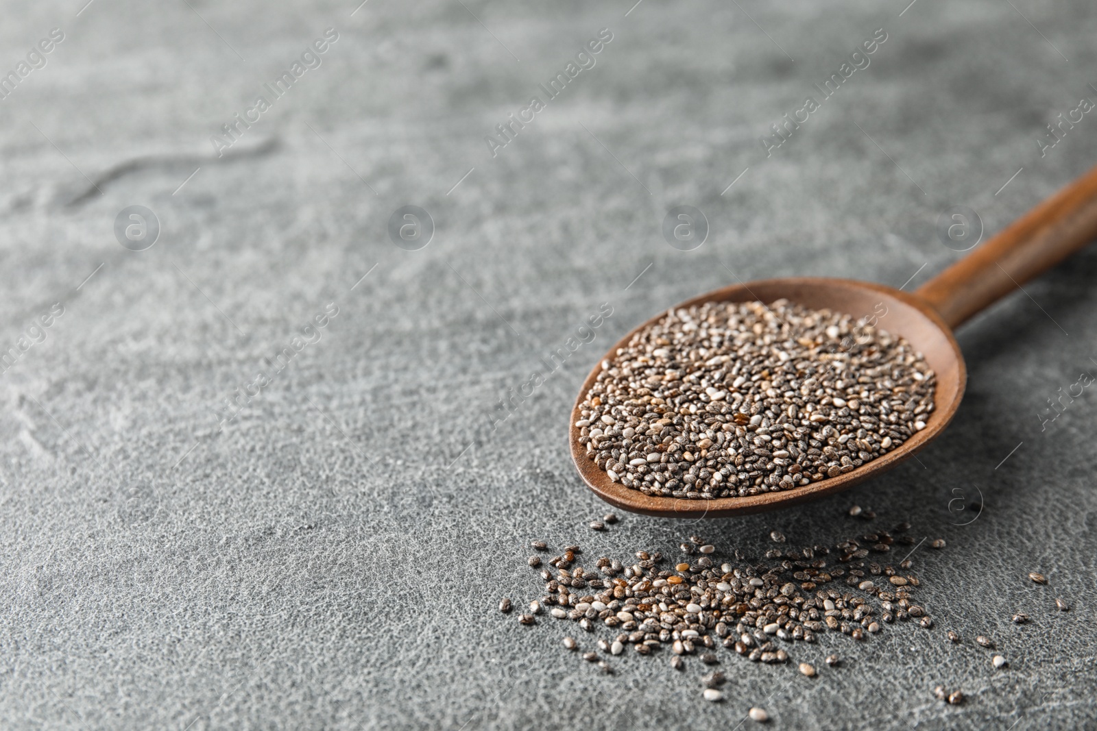 Photo of Spoon with chia seeds on grey background, space for text