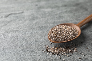 Photo of Spoon with chia seeds on grey background, space for text