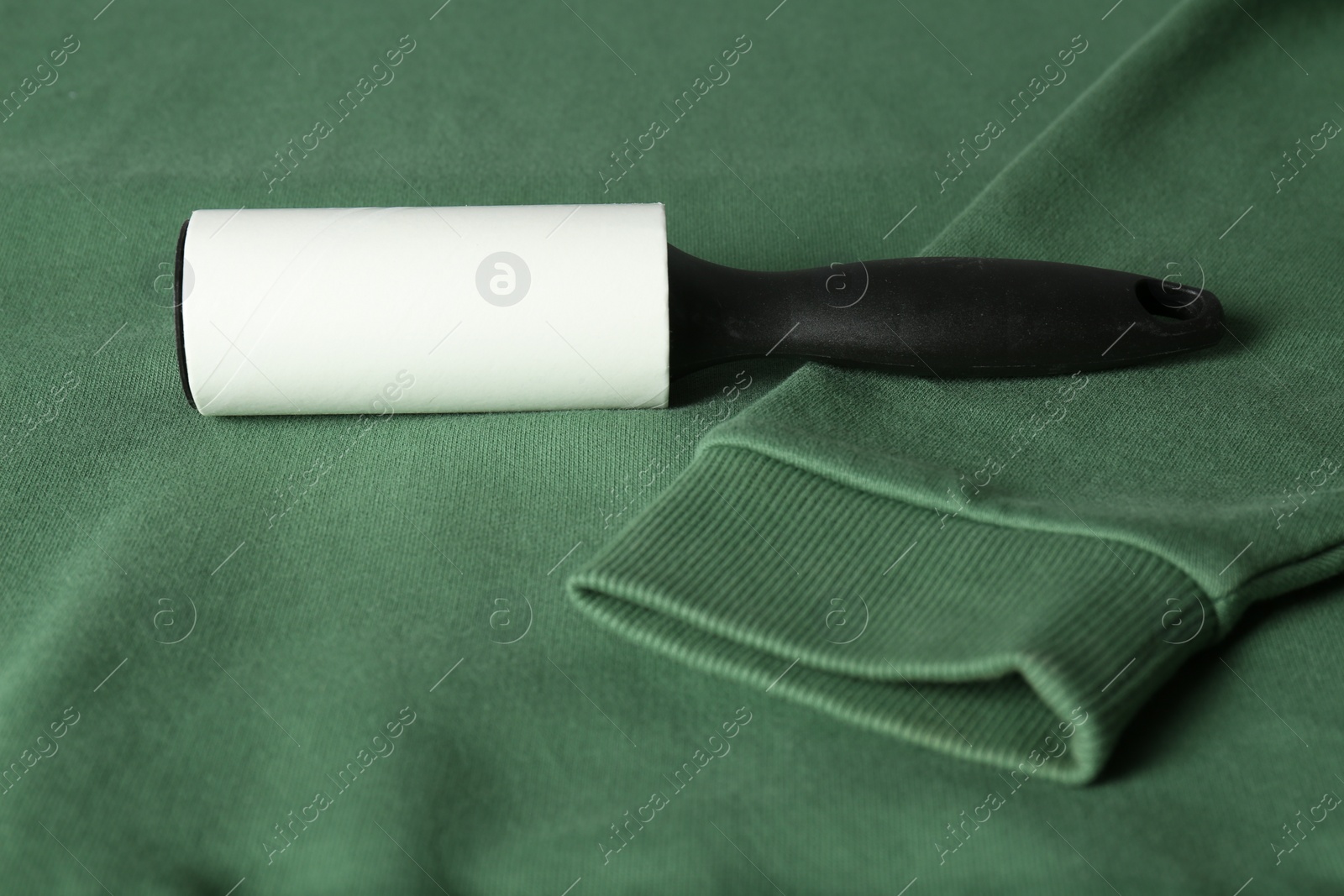 Photo of New lint roller with black handle on green sweatshirt