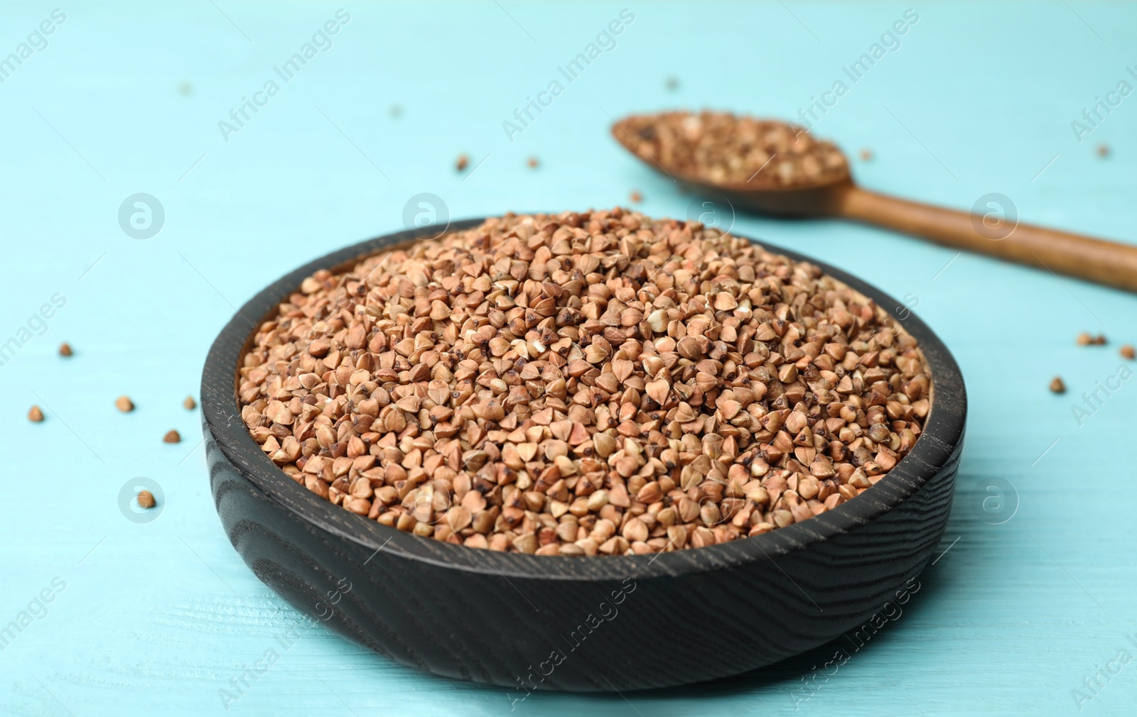 Photo of Buckwheat grains on light blue wooden table